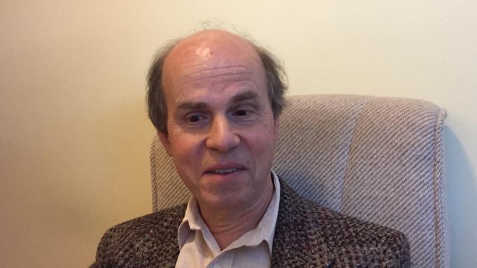 Close-up photo of Glen Gordon.  He is wearing a brown tweed sport coat and beige dress shirt.